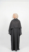 Person wearing a dark gray abaya with a matching headscarf on a white background