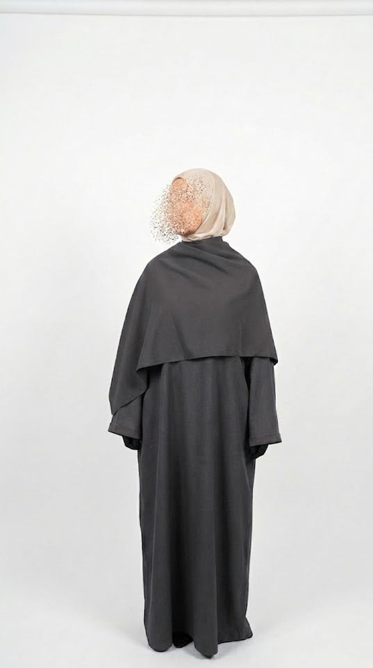 Person wearing a dark gray abaya with a matching headscarf on a white background