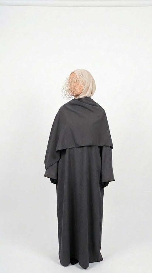Person wearing a dark gray abaya with a matching headscarf on a white background